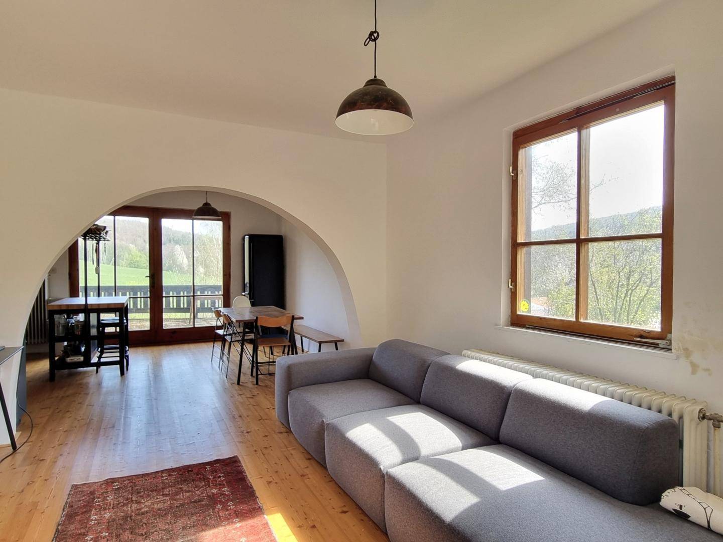 Offener Wohnbereich mit Holzboden, Blick auf den Essbereich und Zugang zur Terrasse.