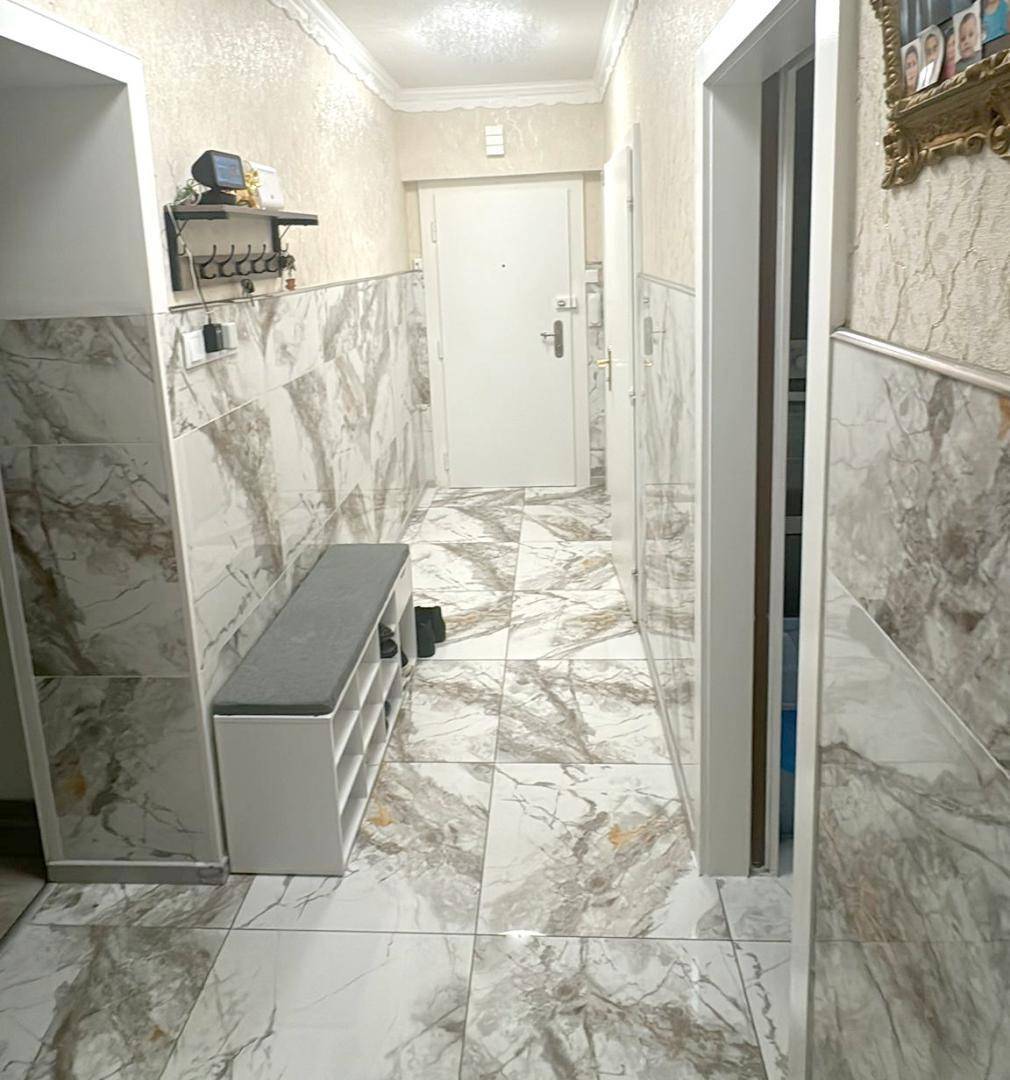 Heller Flur mit Marmorfliesenboden und dekorativer Wandverkleidung.