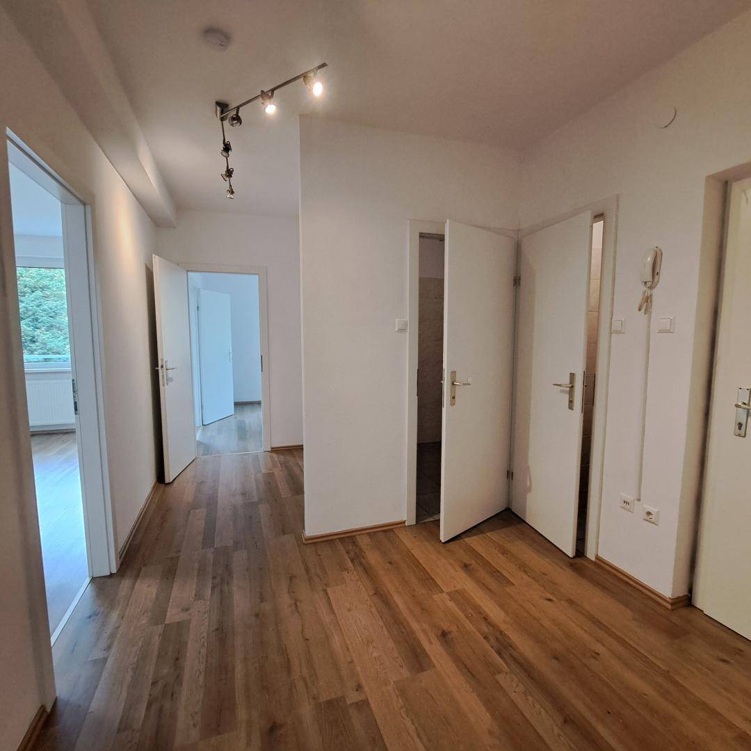 Heller Flur mit Parkettboden und mehreren Türen, die zu den angrenzenden Räumen führen.
