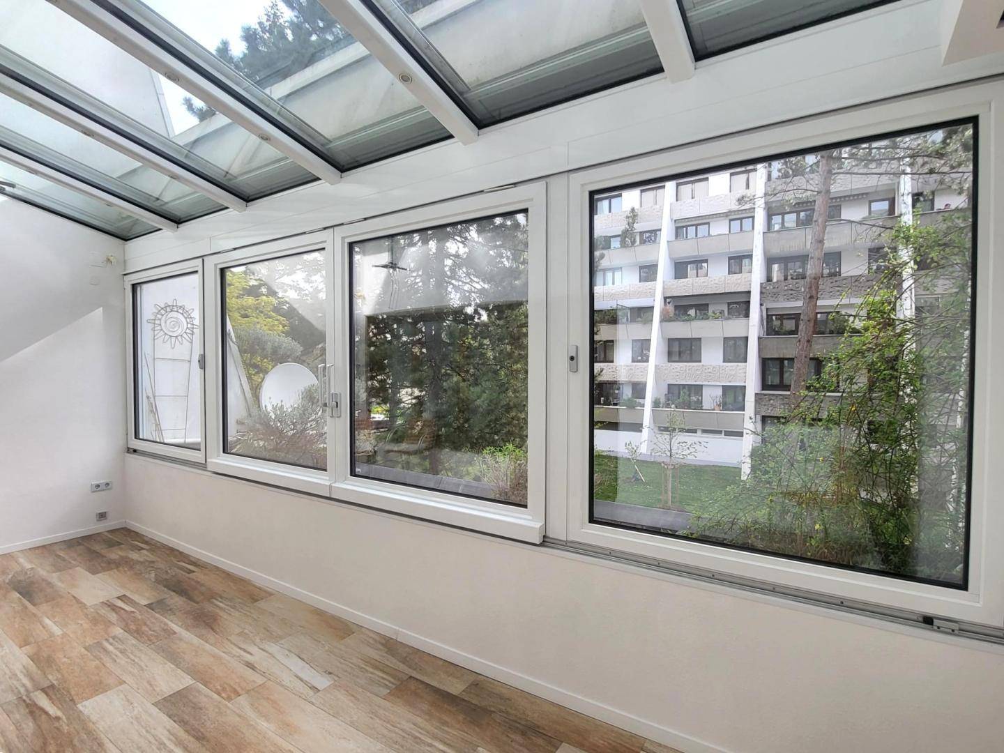 Heller Wintergarten mit Glasdach und großen Fenstern, die einen weiten Blick bieten.