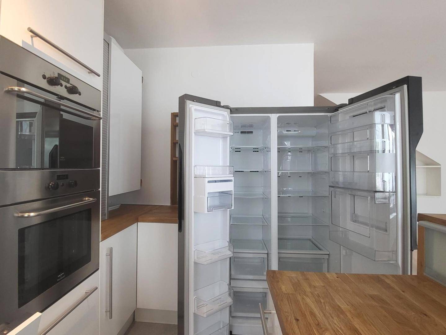 Großer, offener Kühlschrank in der modernen Einbauküche mit Holz-Arbeitsplatten.