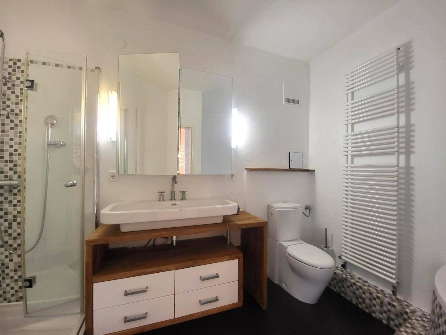 Modernes Badezimmer mit ebenerdiger Dusche, Einzelwaschbecken und beheiztem Handtuchhalter.