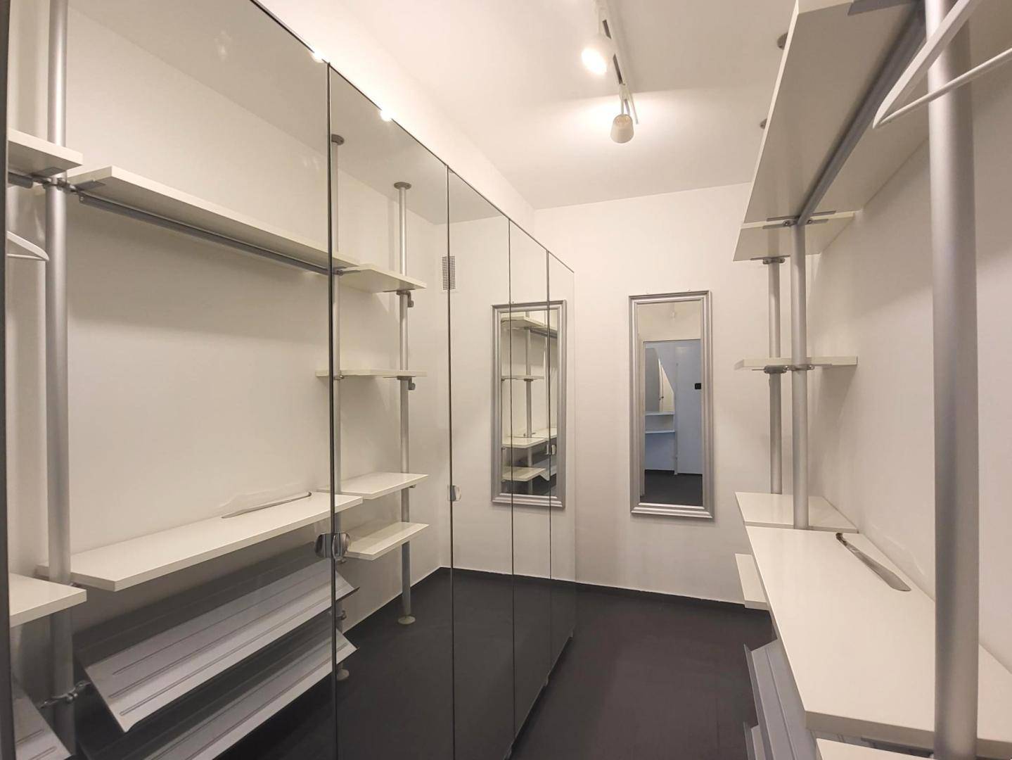 Geräumiger begehbarer Kleiderschrank mit Regalsystemen, Spiegeltüren und viel Stauraum.