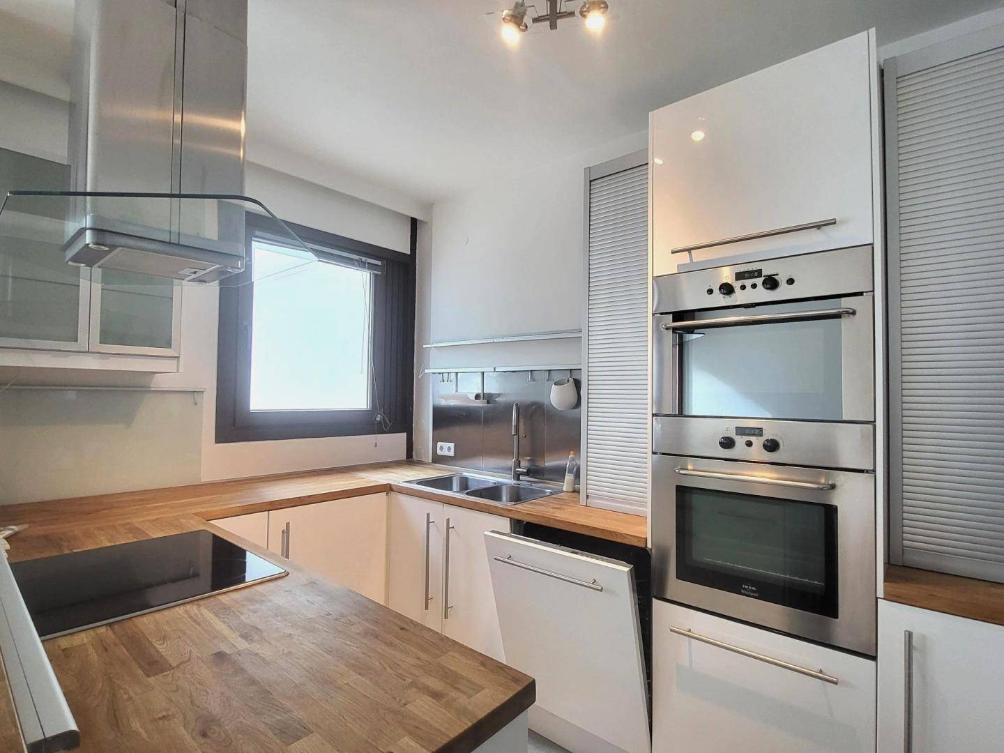 Moderne Küche mit integrierten Backöfen, Induktionskochfeld und Holz-Arbeitsplatten.