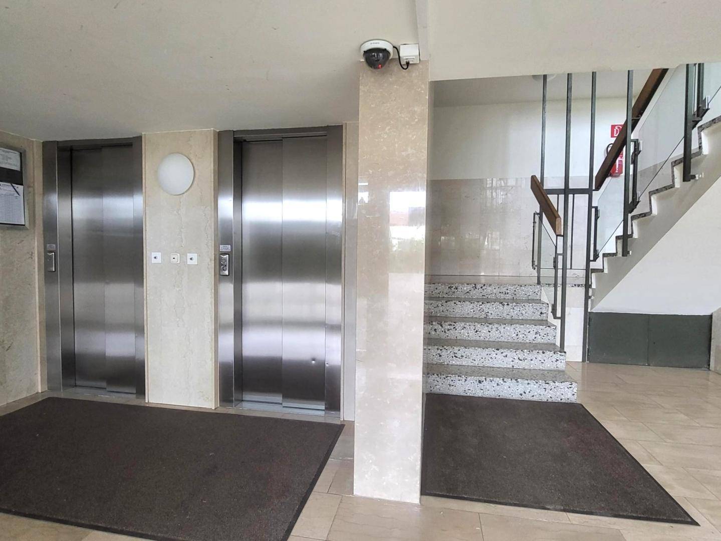 Eingangsbereich des Gebäudes mit zwei Aufzügen, Treppenhaus und barrierefreiem Zugang.