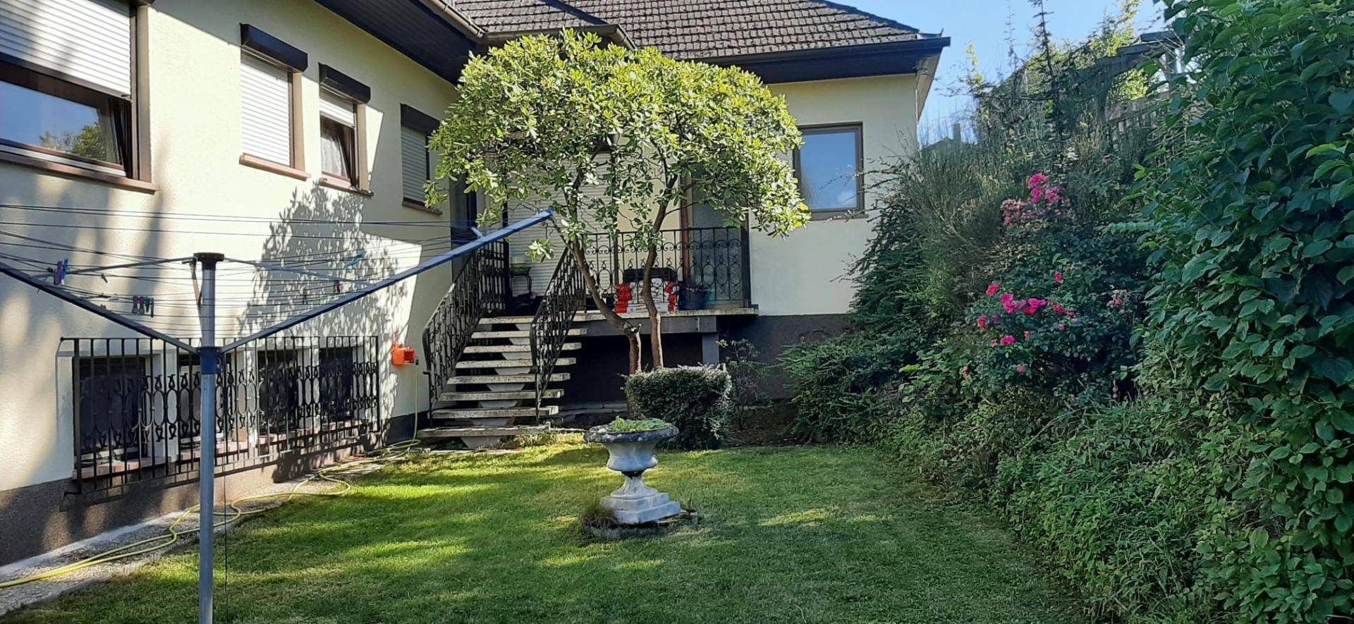 Gepflegter Gartenbereich hinter dem Haus mit Rasenfläche, üppiger Bepflanzung und Wäschespinne.