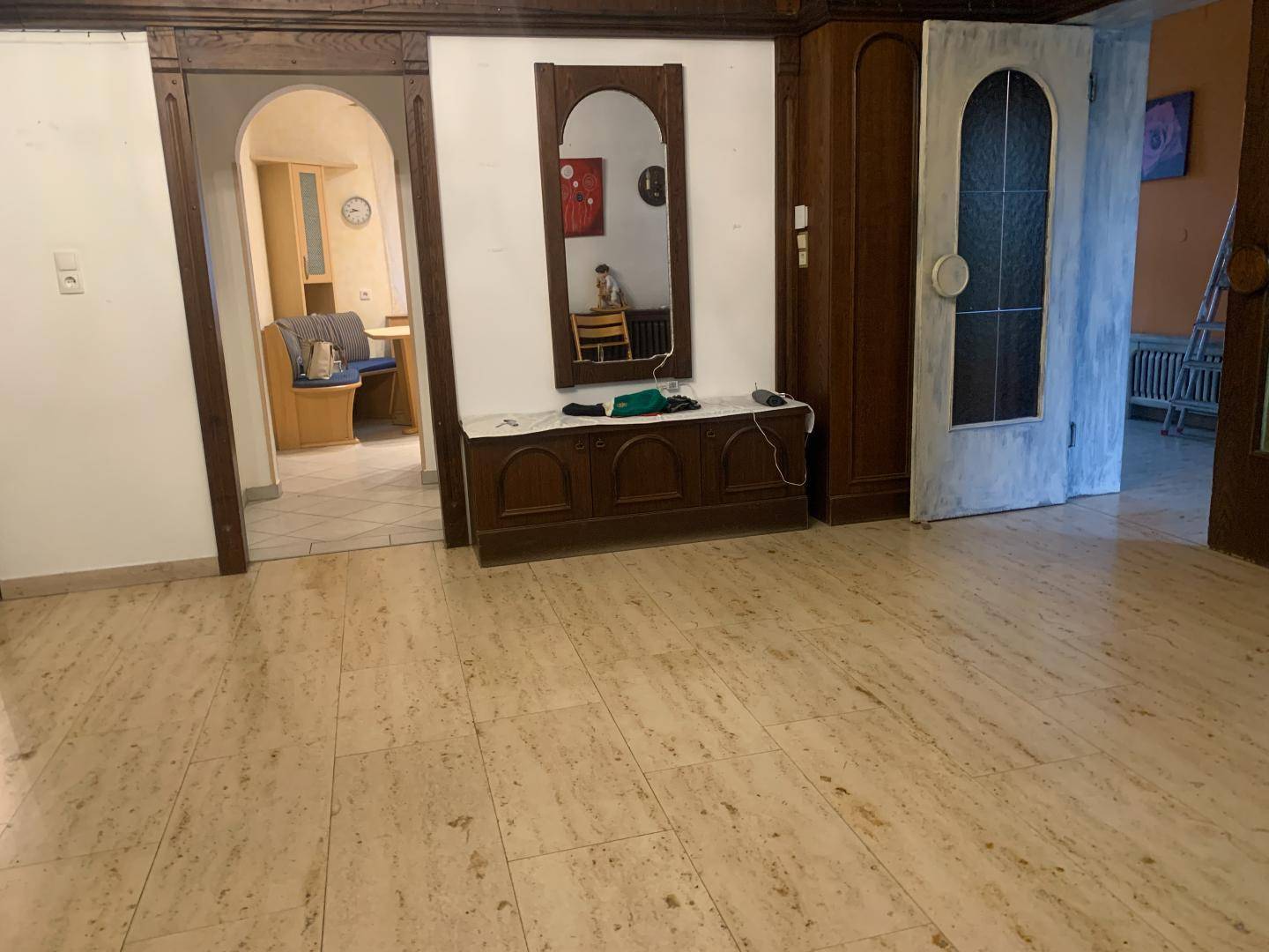 Heller Wohnbereich mit Fliesenboden, Holzmöbeln und einem Spiegel als Dekorationselement.