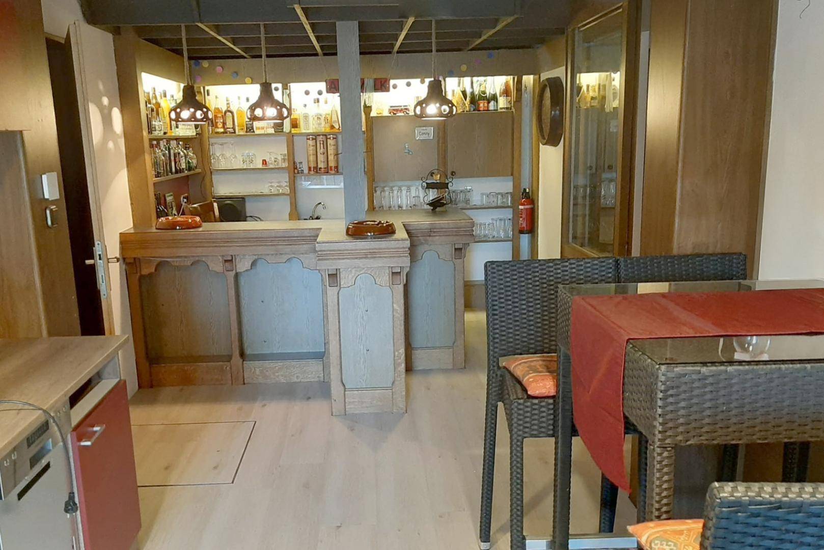 Gemütlicher Barbereich im Keller mit rustikaler Holztheke und Sitzgelegenheiten.