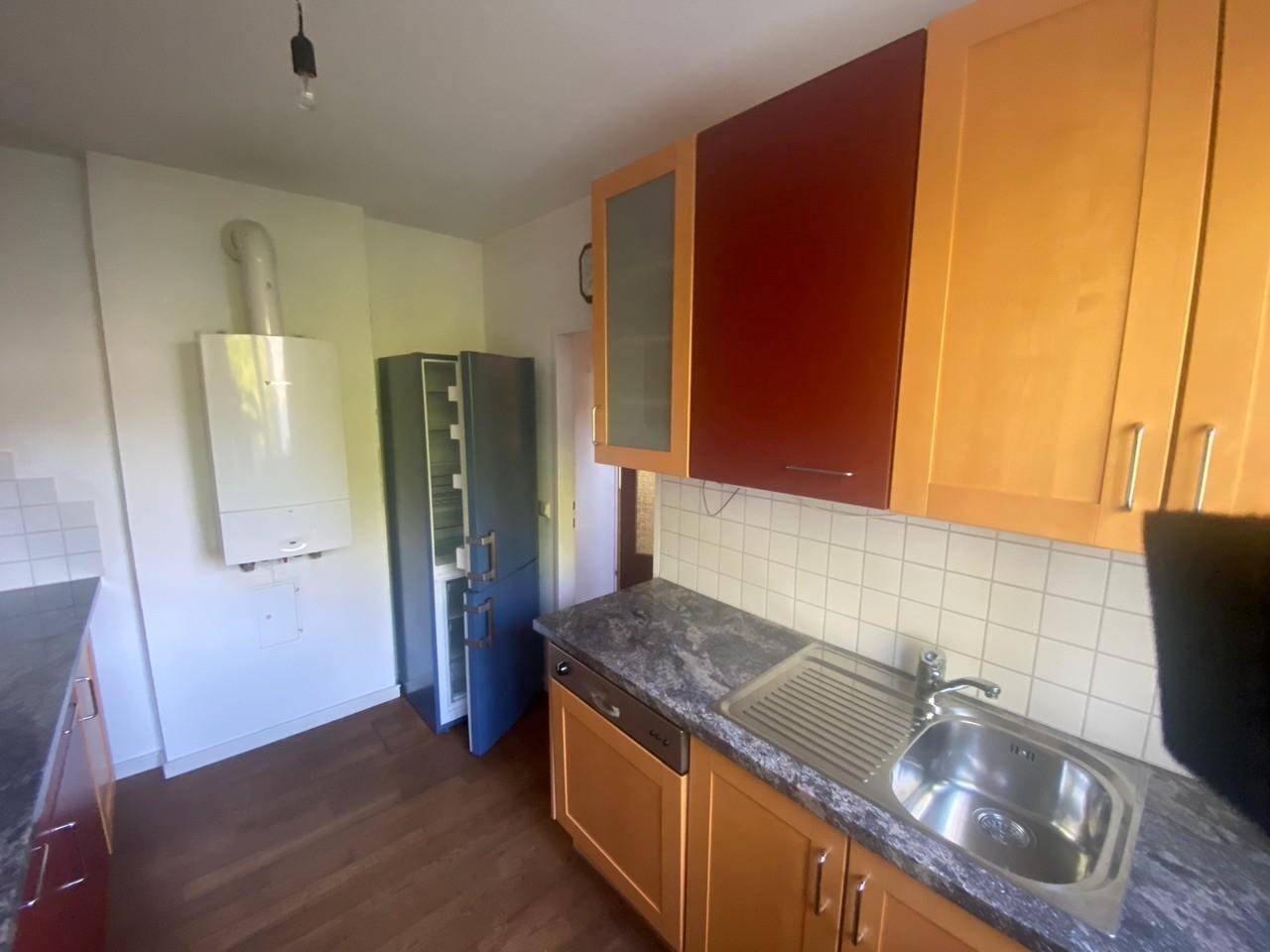 Funktionale Küche mit Holzschränken, integriertem Kühlschrank und einer Gastherme an der Wand.