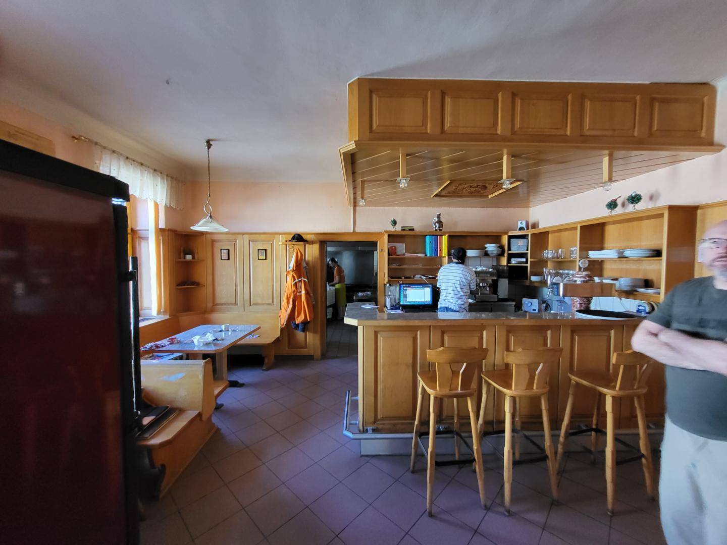 Traditionelle Gaststube mit Holzeinrichtung, Theke und gemütlichen Sitzecken, die eine rustikale Atmosphäre schaffen.