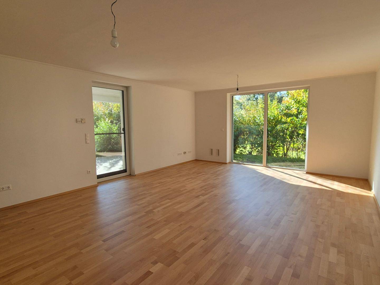 Geräumiges Wohnzimmer mit Parkettboden und direktem Zugang zur Terrasse oder zum Garten.