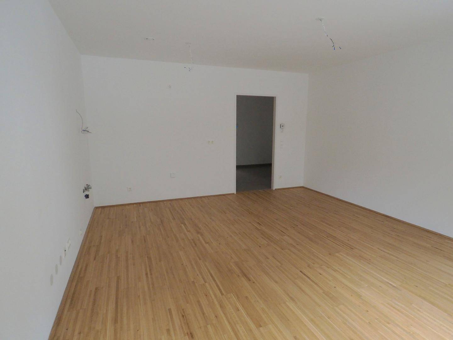 Leeres Zimmer mit Holzboden und weiß gestrichenen Wänden, bereit zum Einzug.