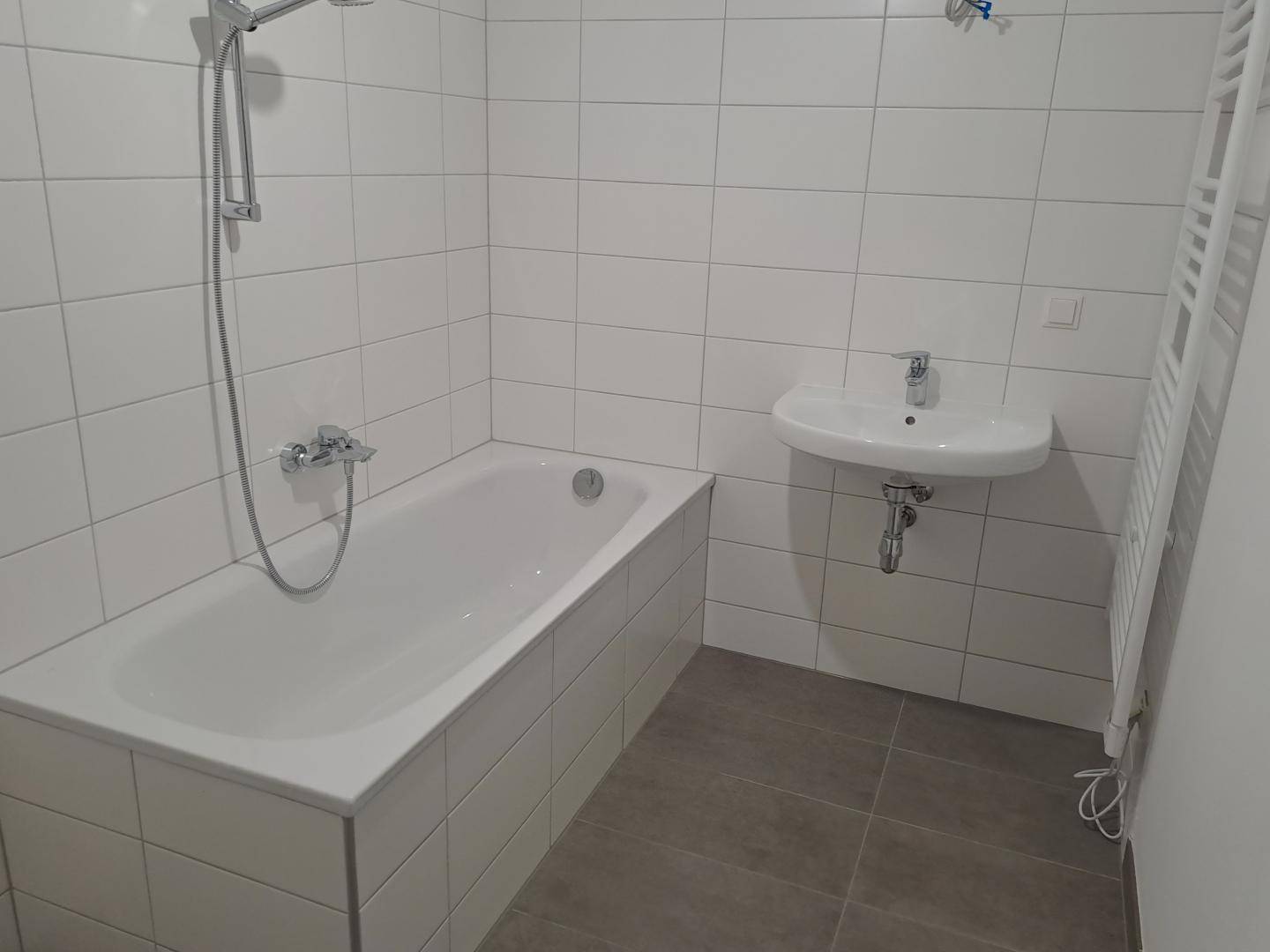 Modernes Badezimmer mit Badewanne, Dusche, Waschbecken und Handtuchheizkörper.