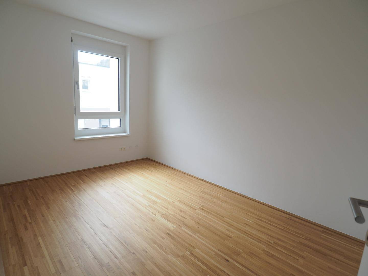 Freundliches Zimmer mit Parkettboden und Fenster, ideal als Kinder- oder Arbeitszimmer.