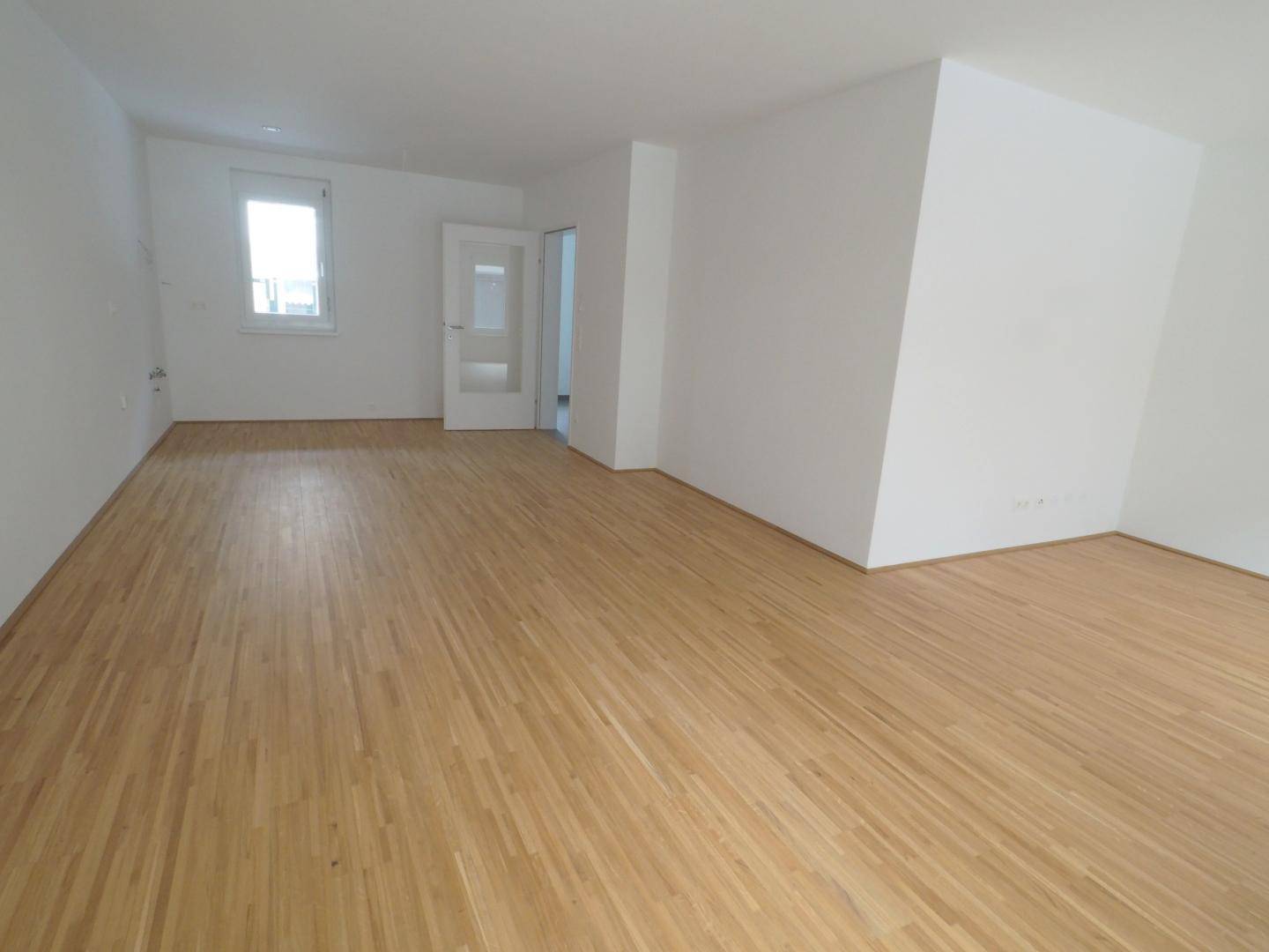 Geräumiges, helles Zimmer mit Parkettboden und einem Fenster, bereit zur Einrichtung.