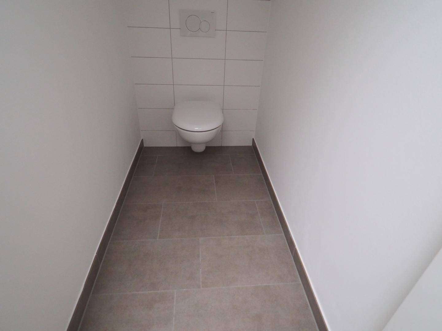 Kleines, funktionales WC mit Fliesenboden und wandhängender Toilette.