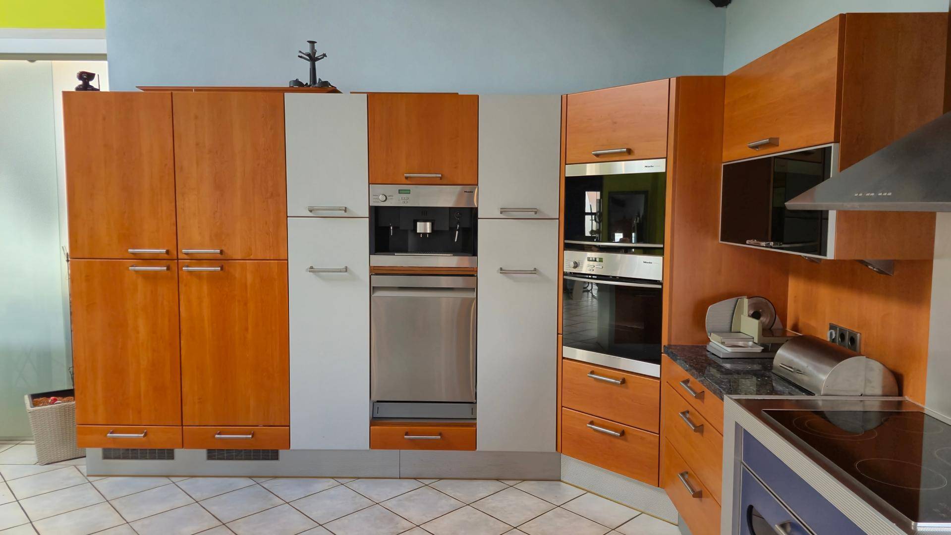 Moderne Einbauküche mit hochwertigen Geräten, darunter Kaffeemaschine und Backofen.