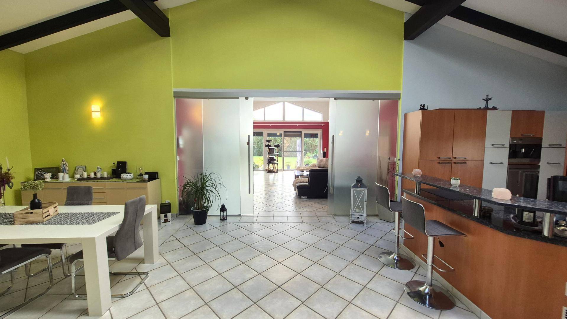 Offener Wohn- und Essbereich mit hohen Decken, Holzbalken und Verbindung zum Wohnzimmer.