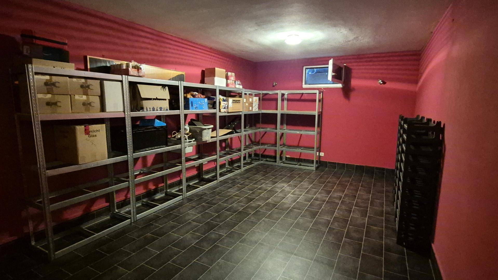 Praktischer Abstellraum im Keller mit Regalsystemen und roter Akzentwand.
