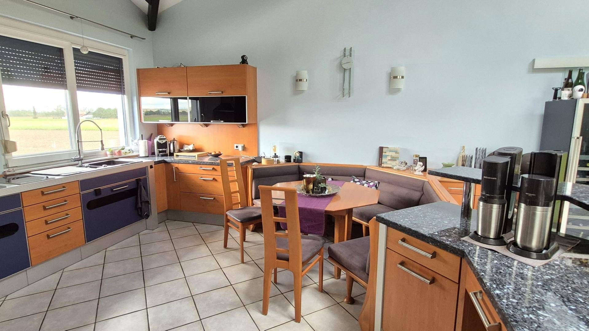 Gemütliche Küche mit integrierter Essecke, Holzelementen und Blick ins Grüne.