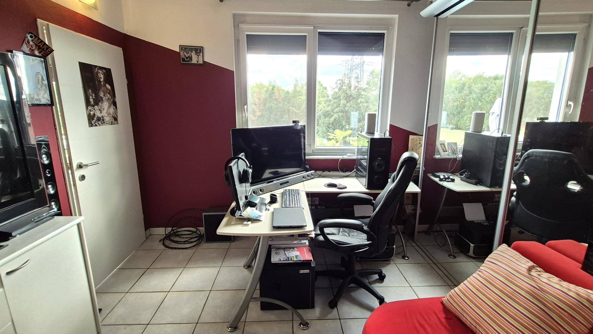 Helles Arbeitszimmer mit großem Fenster, Schreibtisch und Blick ins Grüne.