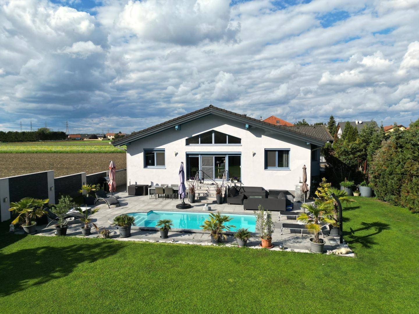 Ansicht des modernen Einfamilienhauses von der Gartenseite mit Pool und Terrasse.