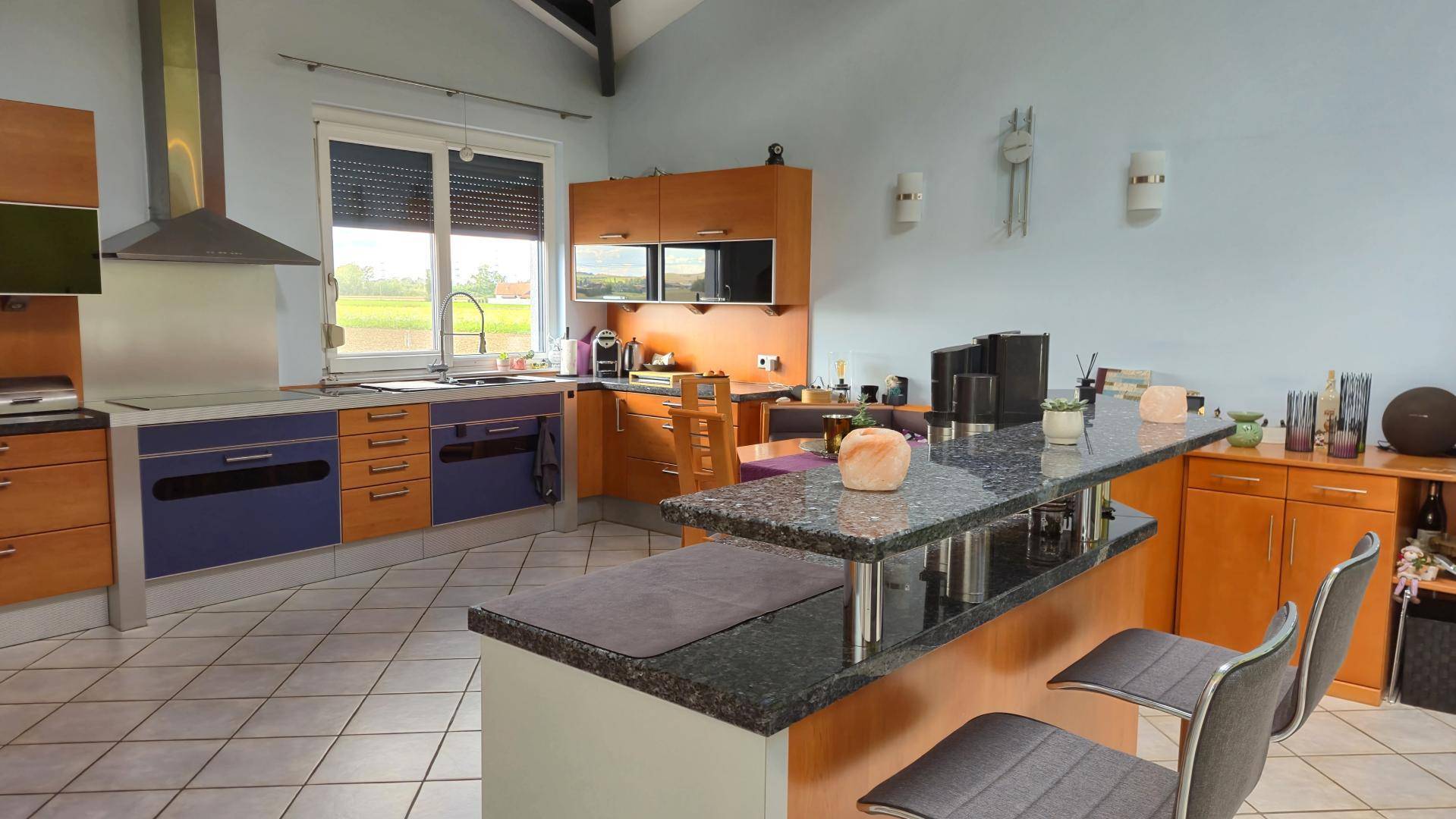 Moderne Küche mit Frühstücksbar, dunkler Arbeitsplatte und Blick nach draußen.