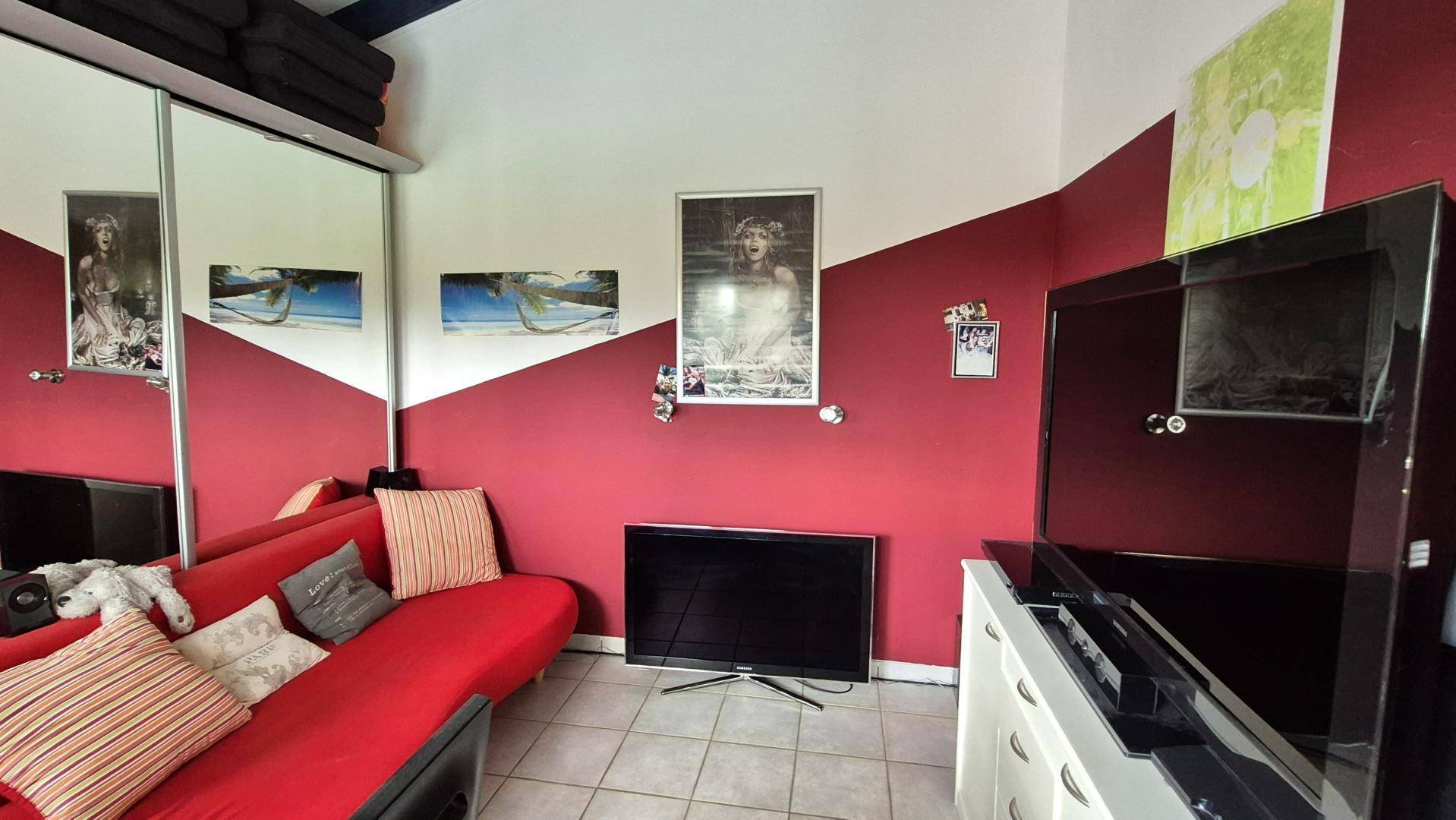 Schlafzimmer mit roter Akzentwand, Spiegelschränken und modernem Interieur.