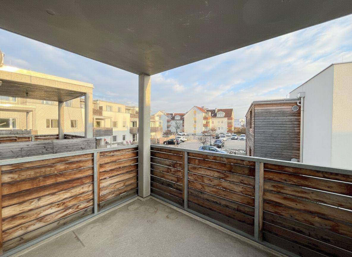 Balkon mit Holzverkleidung und Blick auf die umliegenden Gebäude und die Straße.
