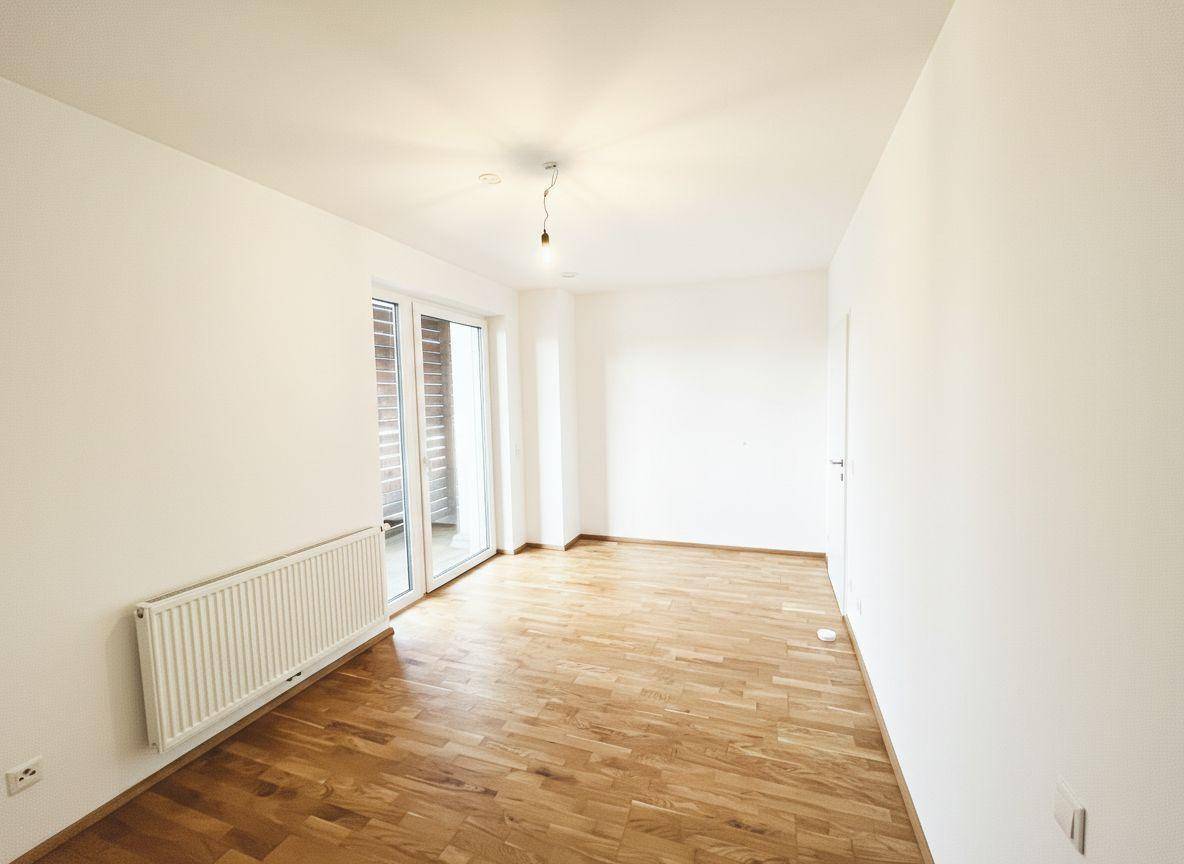 Freundliches Zimmer mit Parkettboden, weißen Wänden und direktem Zugang zum Außenbereich.