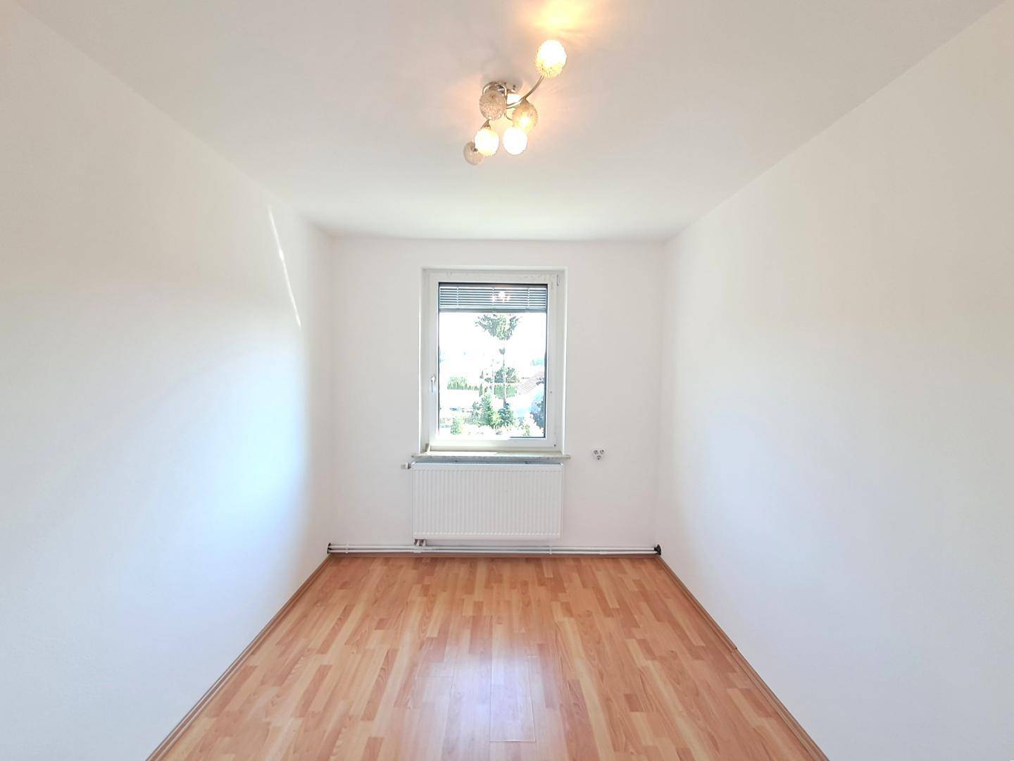 Freundliches Zimmer mit Laminatboden und Fenster, ideal als Schlaf- oder Arbeitszimmer nutzbar.
