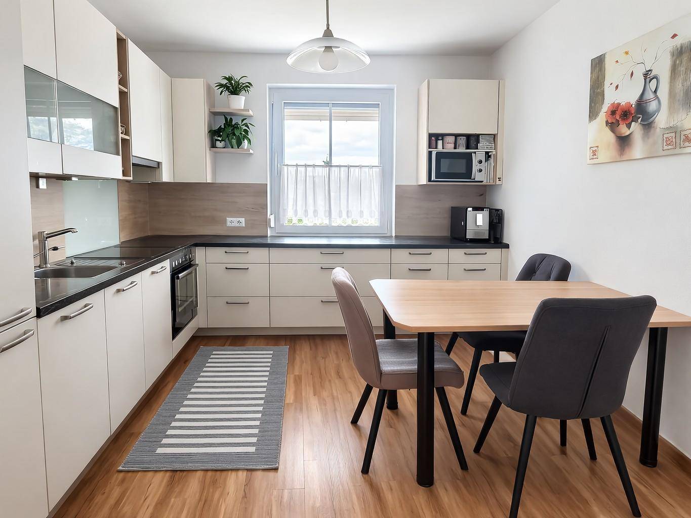 Moderne Einbauküche mit hellem Holzdekor, Essbereich und Fenster.