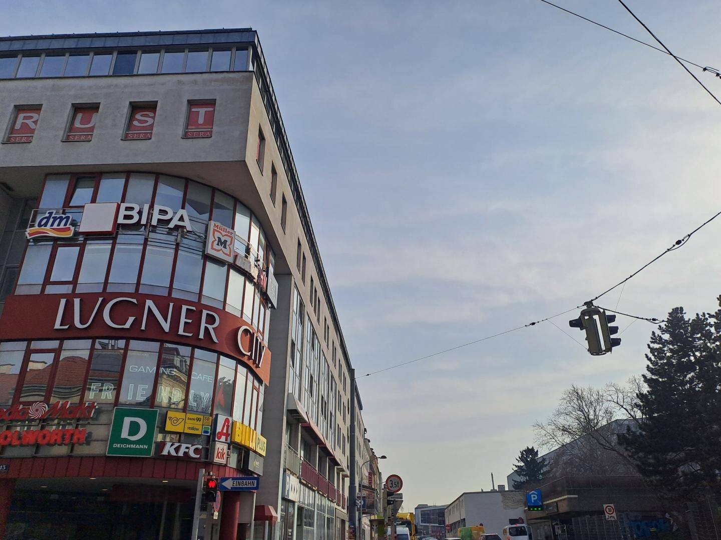 Großes Geschäftsgebäude mit vielen Geschäften und Büros in einer belebten Stadtansicht.