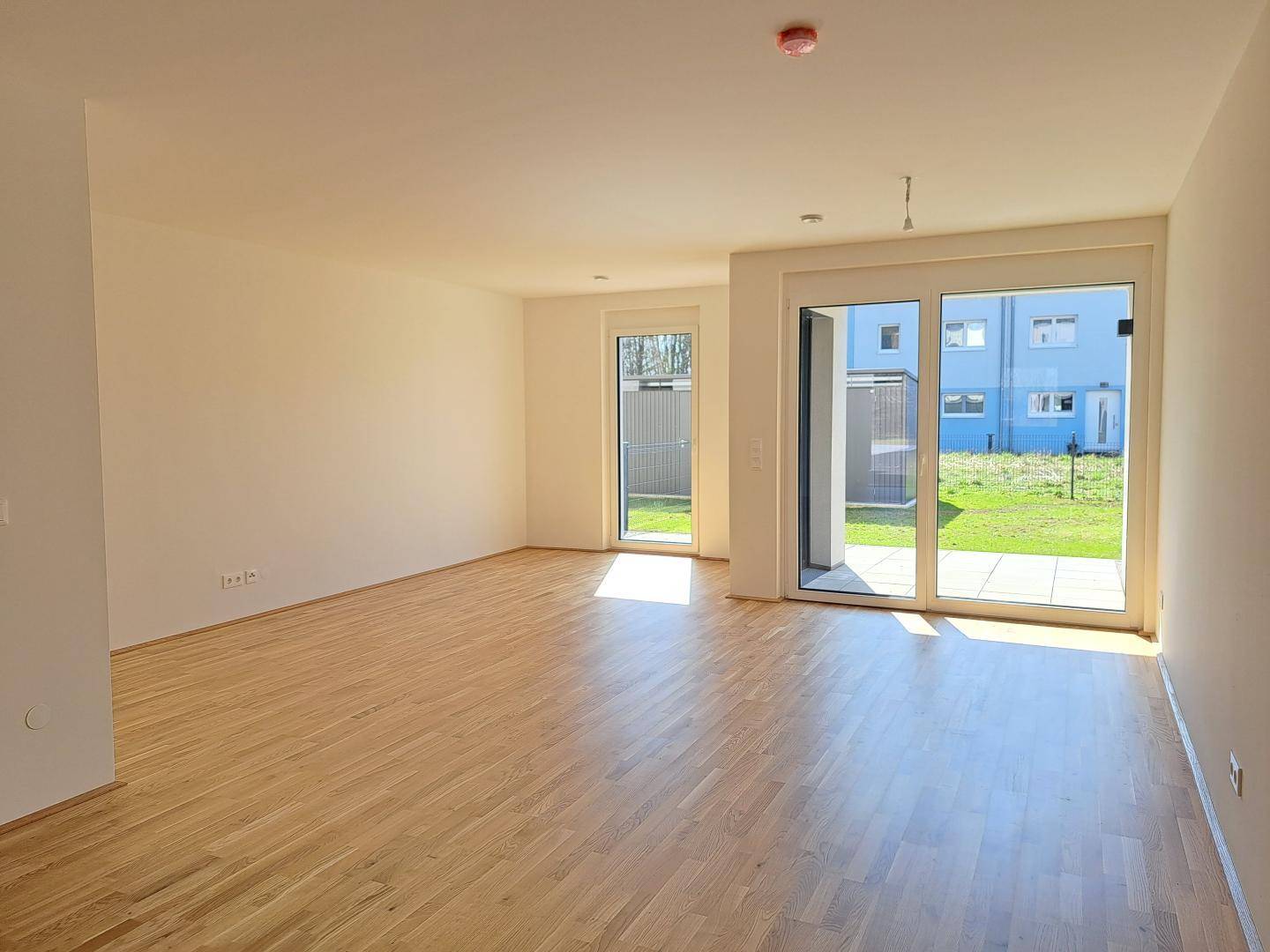 Geräumiges, helles Wohnzimmer mit Parkettboden und Zugang zur Terrasse und zum Garten.