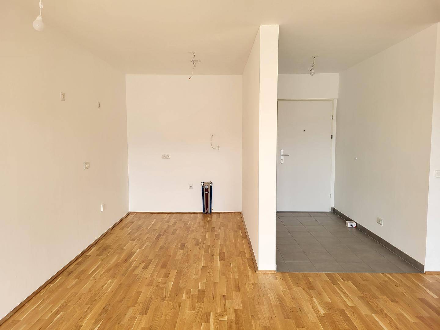 Eingangsbereich mit Parkettboden, der in einen gefliesten Flur übergeht.