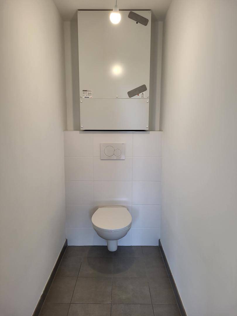 Separates WC mit wandhängender Toilette und modernen Fliesen.