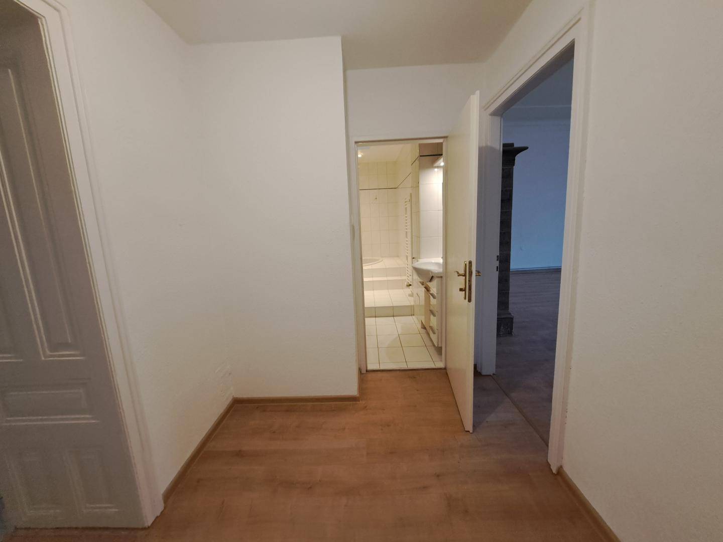 Heller Flur mit Laminatboden und Zugang zu verschiedenen Zimmern.