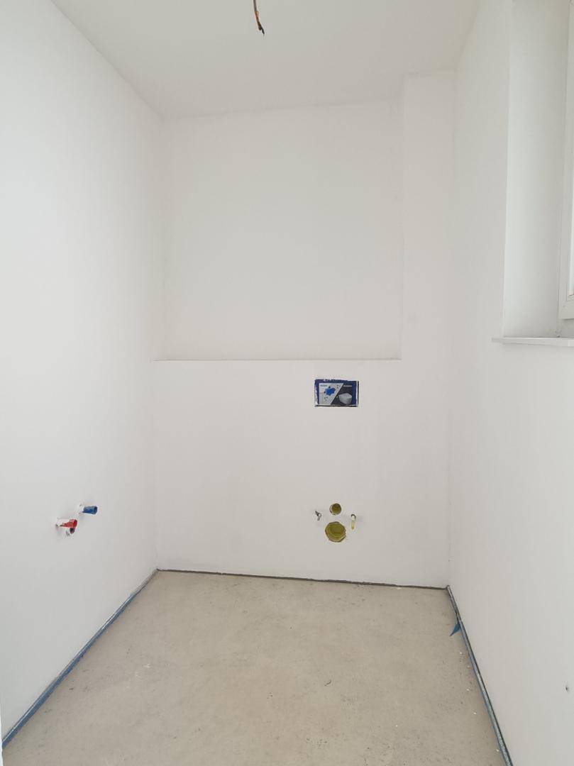 Kleiner Raum im Rohbau mit vorbereiteten Anschlüssen für ein Gäste-WC oder Bad.