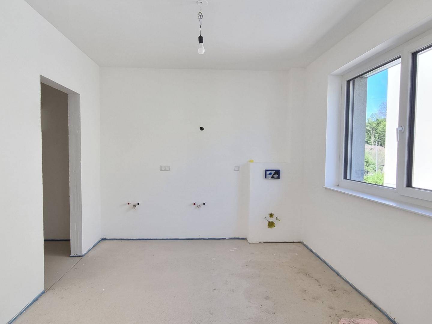 Geräumiges Badezimmer im Rohbau mit vorbereiteten Anschlüssen und viel Tageslicht.