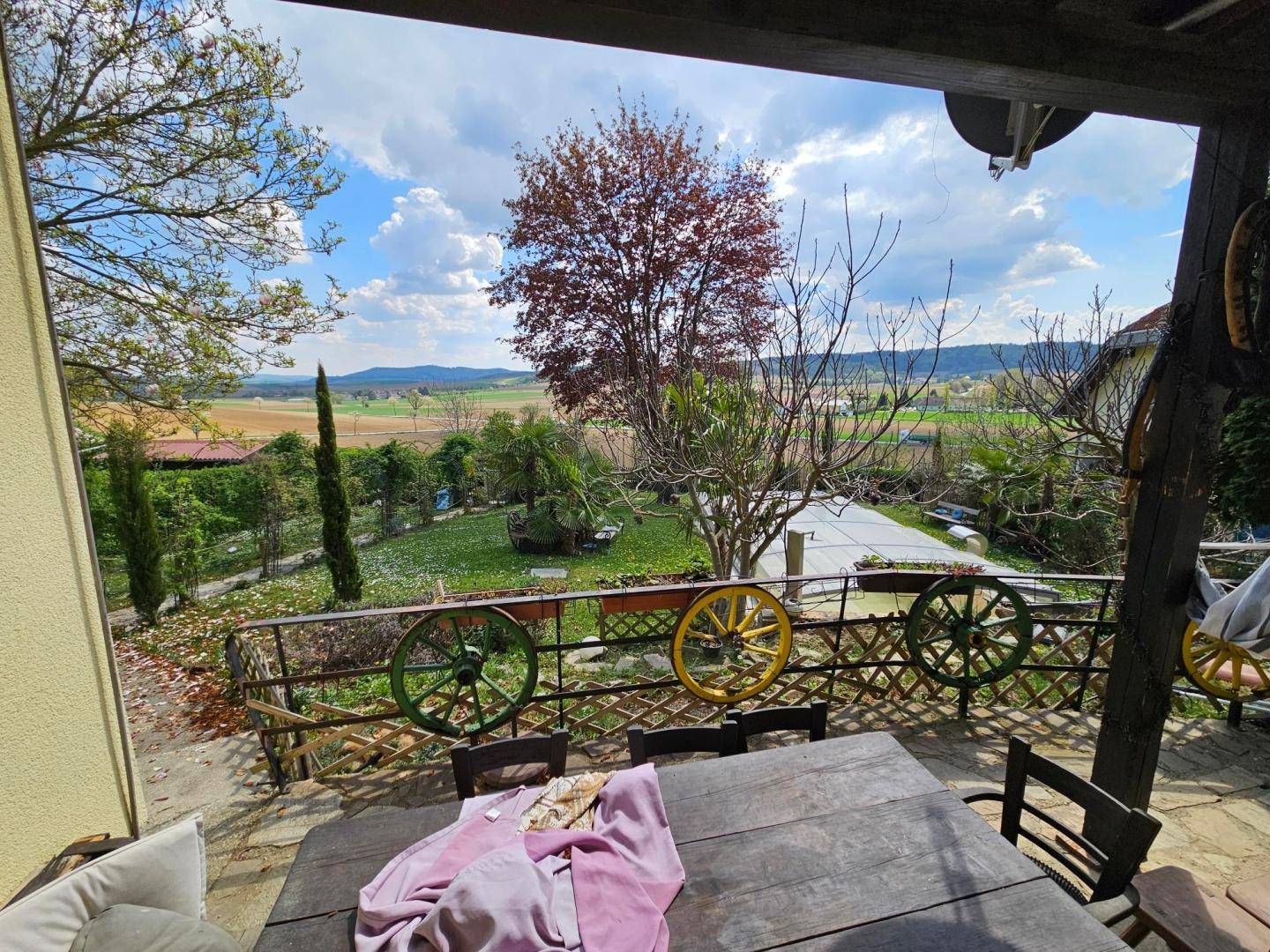 Überdachte Terrasse mit Esstisch und weitem Blick über die Landschaft.