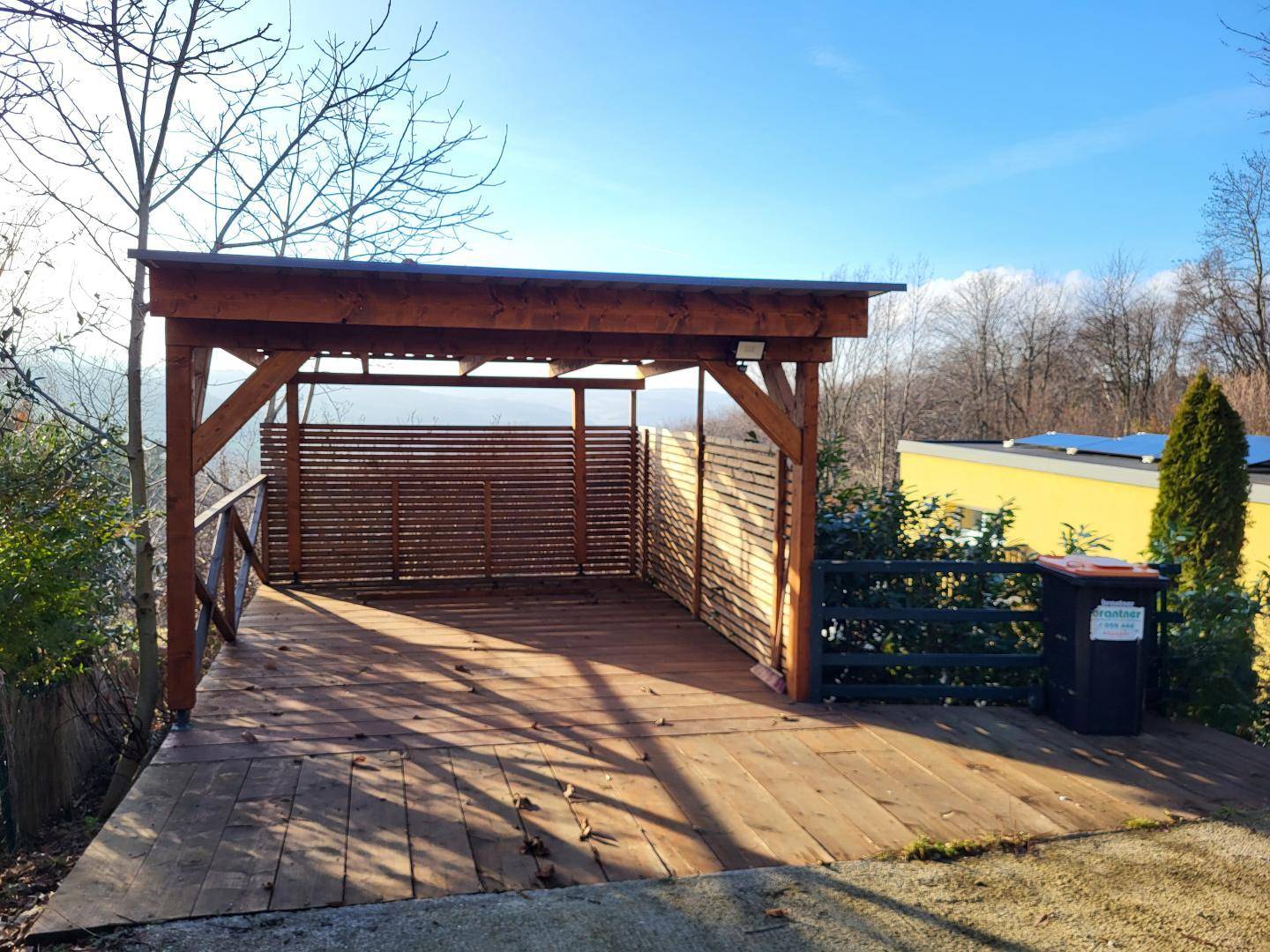 Offener Holzcarport mit weitem Blick über die Landschaft, ideal für Fahrzeuge.