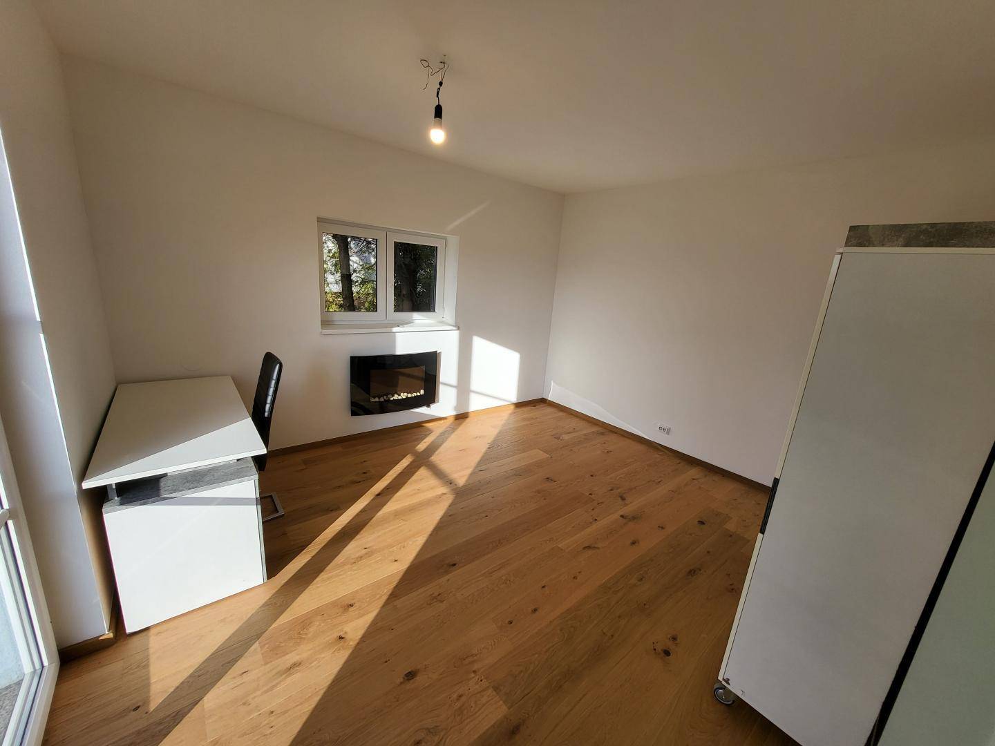 Helles Arbeitszimmer mit Holzboden, integriertem Kamin und Blick ins Freie.