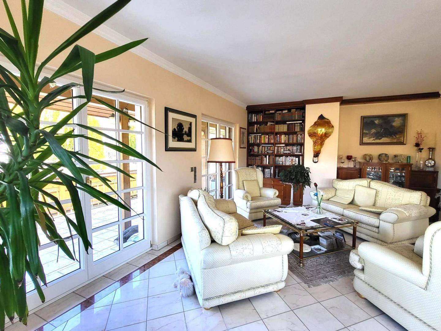 Helles Wohnzimmer mit Zugang zu einem Balkon, großen Fenstern und bequemen Sitzgelegenheiten für gesellige Stunden.