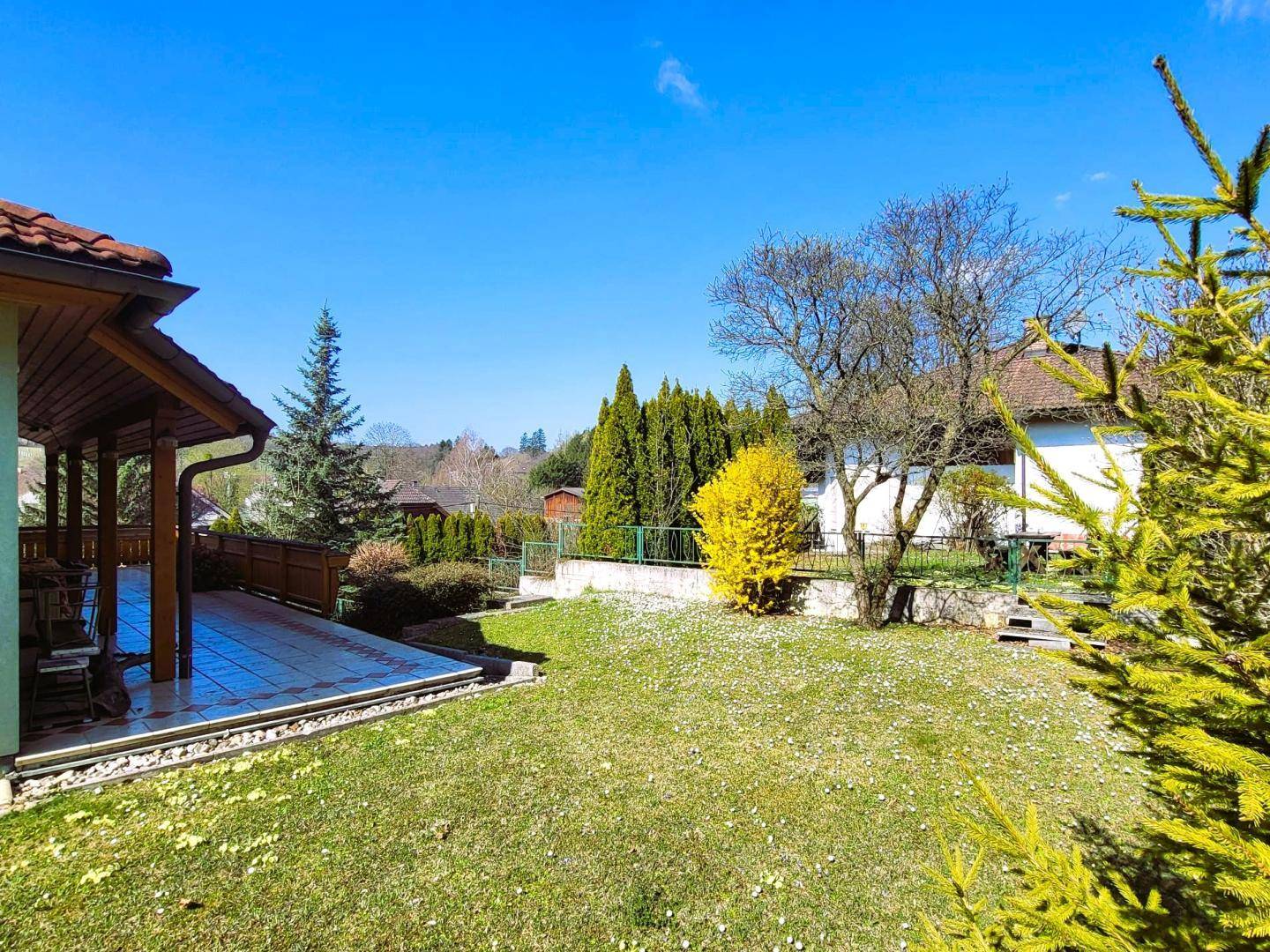 Gepflegter Garten mit Rasenfläche und einer überdachten Terrasse, die zum Verweilen im Freien einlädt.