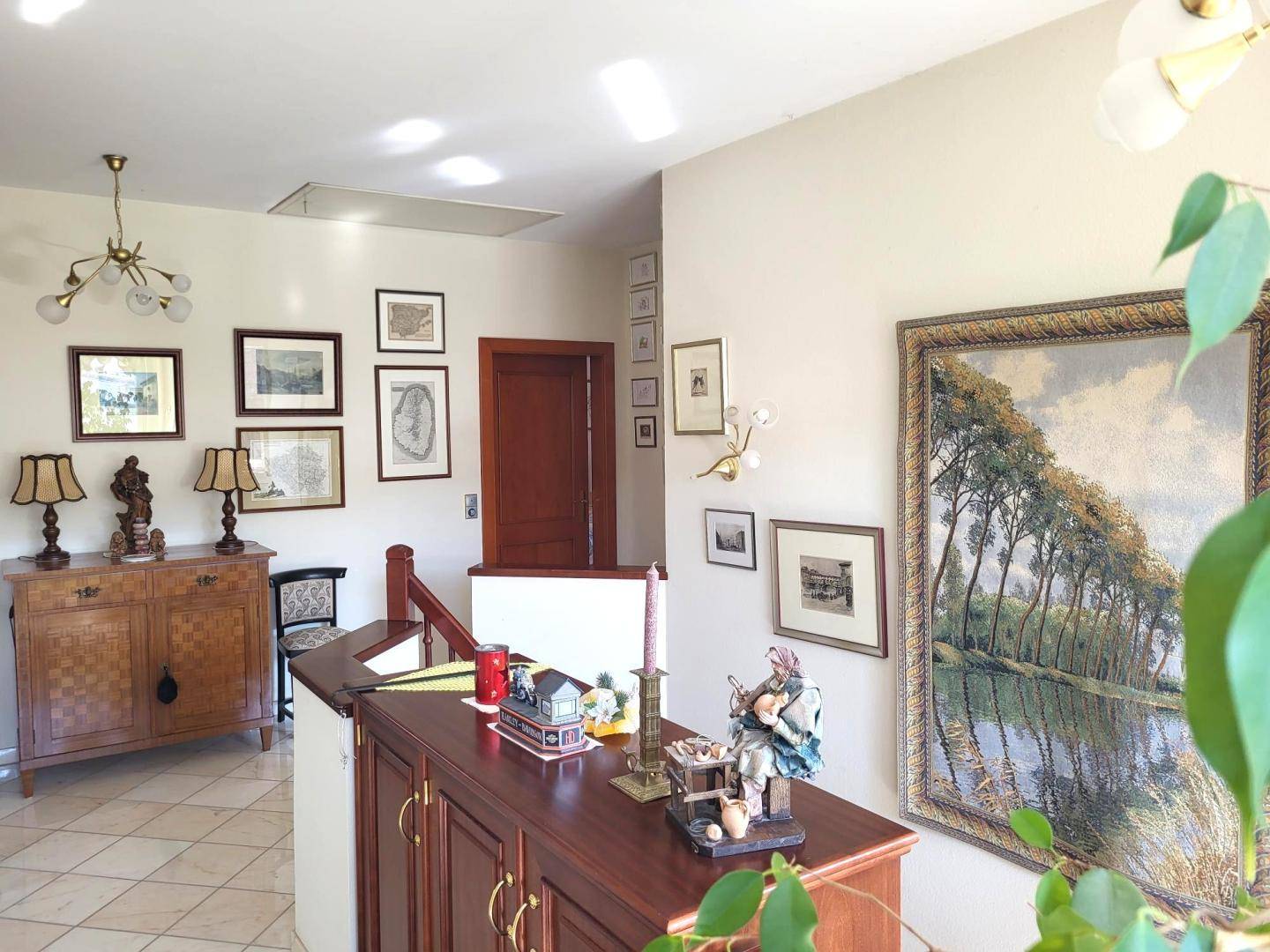 Geräumiger Flur mit traditionellen Möbeln, Kunstwerken an den Wänden und einem Blick auf die obere Etage.