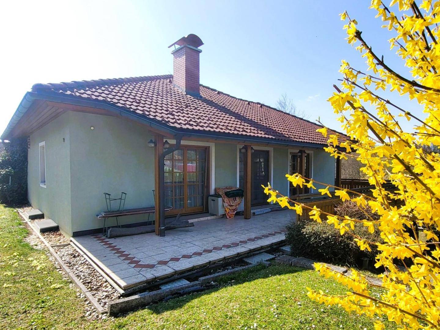 Rückansicht des Hauses mit einer großen, gefliesten Terrasse und einem gepflegten Gartenbereich.