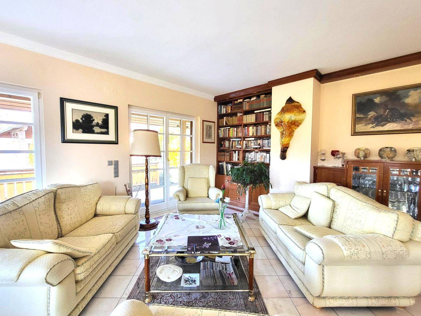 Gemütliches Wohnzimmer mit beigen Sofas, einem Bücherregal und einem Couchtisch, ideal zum Entspannen.