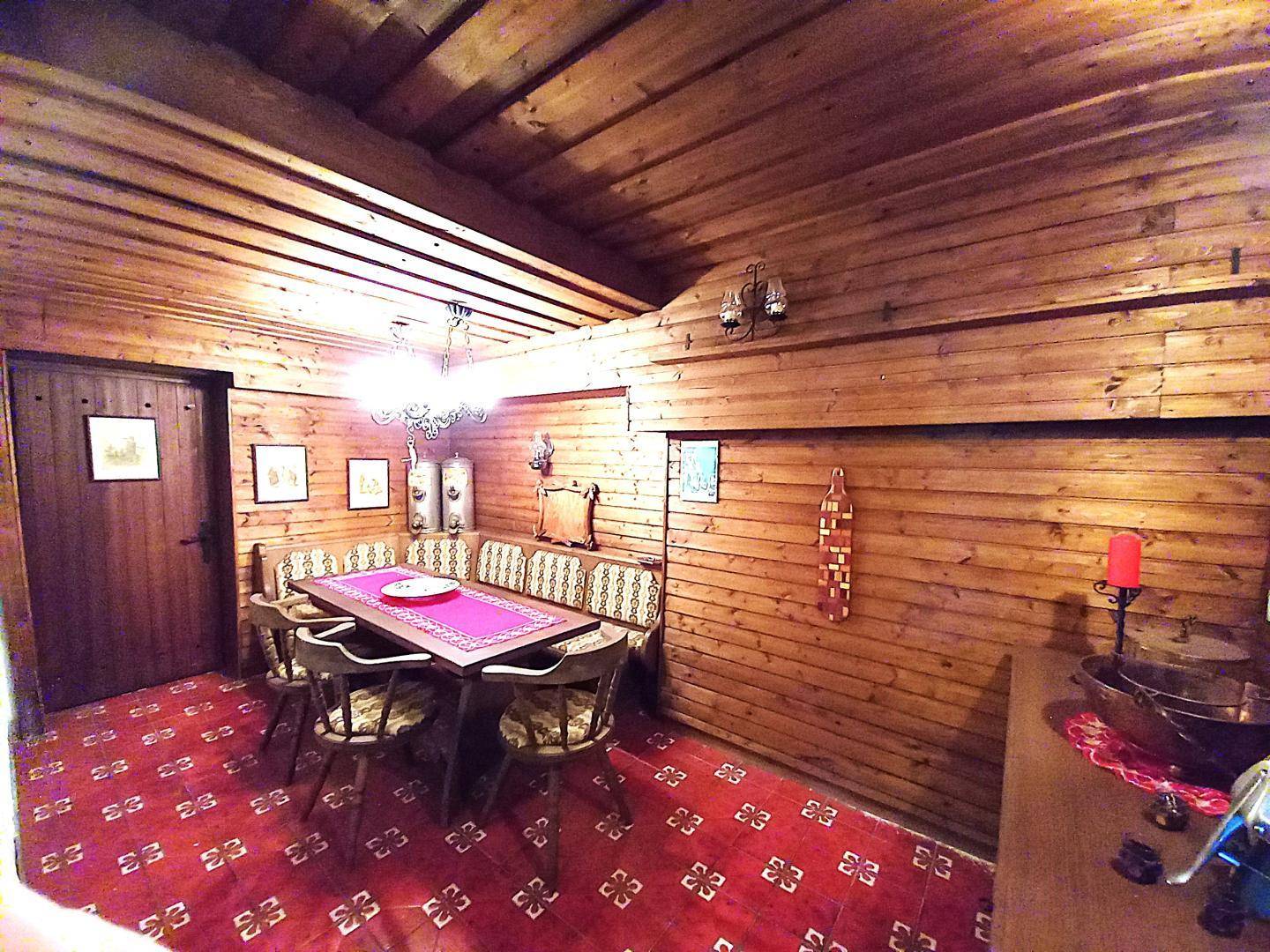 Rustikaler Essbereich mit Holztäfelung an Wänden und Decke, einer Eckbank und traditionellen Möbeln.