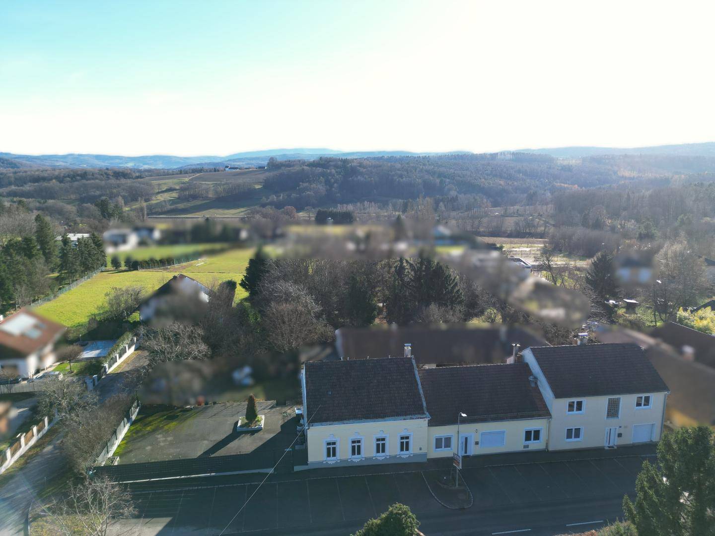 Luftaufnahme des Anwesens mit umliegender Landschaft und grünen Hügeln im Hintergrund.