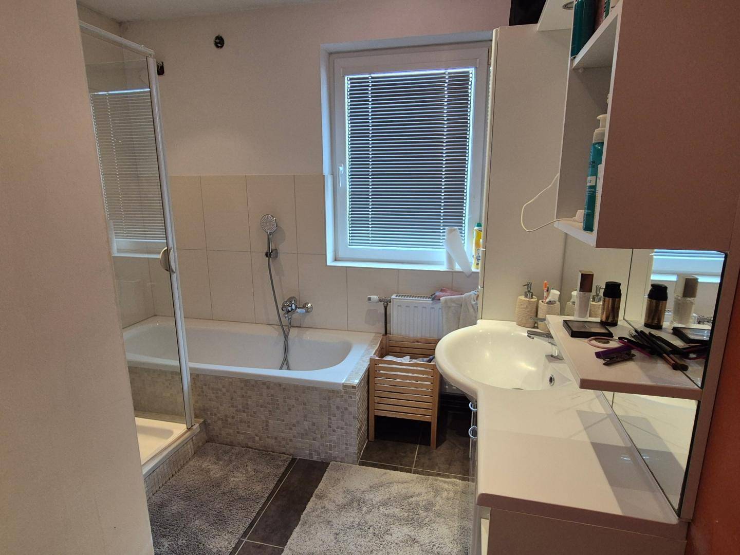 Funktionales Badezimmer mit Badewanne, Duschkabine, Waschbecken und Fenster.